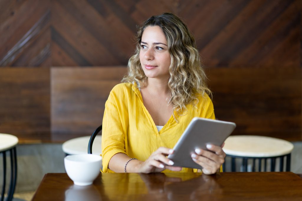 pensive pretty young woman sitting at cafe table with table